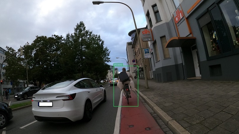 Eine Person auf einem Fahrrad fährt auf einem Fahrradweg neben einem Auto Eine Person auf einem Fahrrad fährt auf einem Fahrradweg neben einem Auto