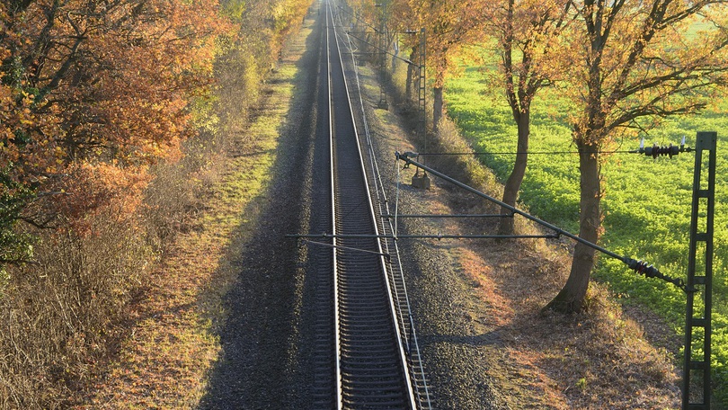 Bahnschiene neben herbstlichen Bäumen und Feld Bahnschiene neben herbstlichen Bäumen und Feld