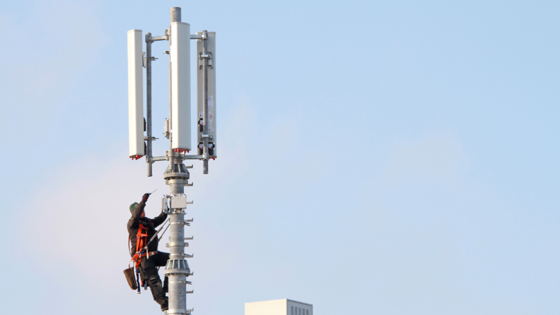 Eine Person arbeitet an einem Mobilfunkmast Eine Person arbeitet an einem Mobilfunkmast