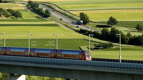 Eine Regionalbahn fährt über eine Eisenbahnbrücke durch eine vorwiegend grüne Landschaft Eine Regionalbahn fährt über eine Eisenbahnbrücke durch eine vorwiegend grüne Landschaft