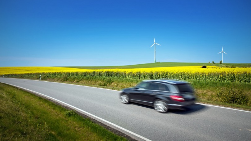 Fahrendes Auto vor Rapsfeld und Windkrafträdern Fahrendes Auto vor Rapsfeld und Windkrafträdern