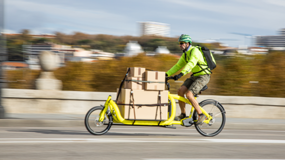 Ein Lieferant transportiert Pakete mit einem Lastenfahrrad Ein Lieferant transportiert Pakete mit einem Lastenfahrrad