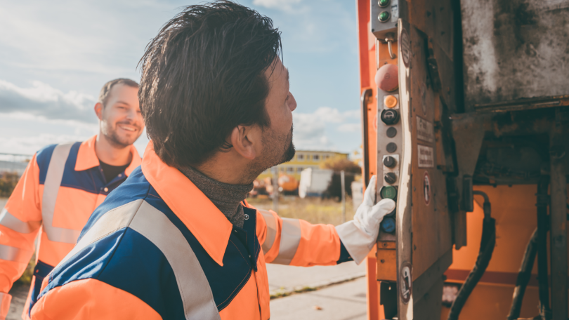 Zwei Männer arbeiten an einem Abfallsammelfahrzeug Zwei Männer arbeiten an einem Abfallsammelfahrzeug
