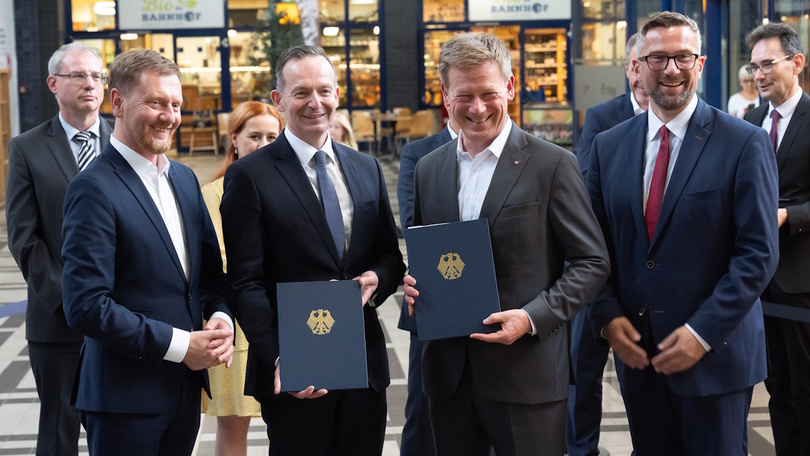 Gruppenfoto mit Volker Wissing und Richard Lutz, die beide eine Dokumentenmappe mit Bundesadler in die Kamera halten Gruppenfoto mit Volker Wissing und Richard Lutz, die beide eine Dokumentenmappe mit Bundesadler in die Kamera halten