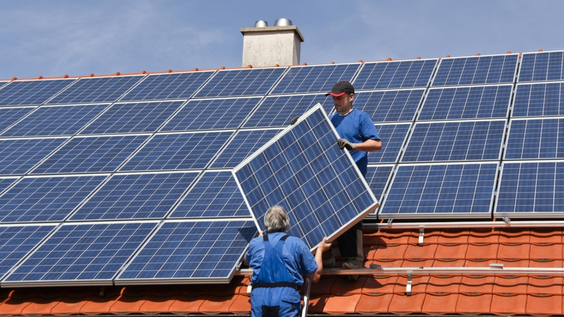 Zwei Arbeiter montieren eine Photovoltaik-Anlage auf dem Dach eines Hauses Zwei Arbeiter montieren eine Photovoltaik-Anlage auf dem Dach eines Hauses