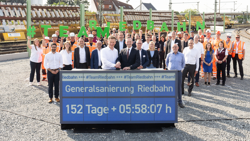 Volker Wissing beim Team Riedbahn um die Sanierung zu starten. Im Hintergrund ist eine größere Gruppe von Mitarbeitern der Riedbahn zu sehen. Volker Wissing beim Team Riedbahn um die Sanierung zu starten. Im Hintergrund ist eine größere Gruppe von Mitarbeitern der Riedbahn zu sehen.