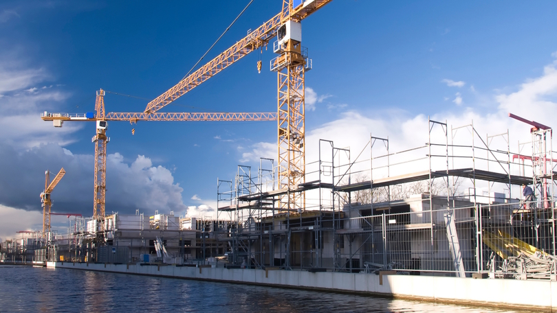 Baustelle mit Kränen direkt neben einem Fluss Baustelle mit Kränen direkt neben einem Fluss