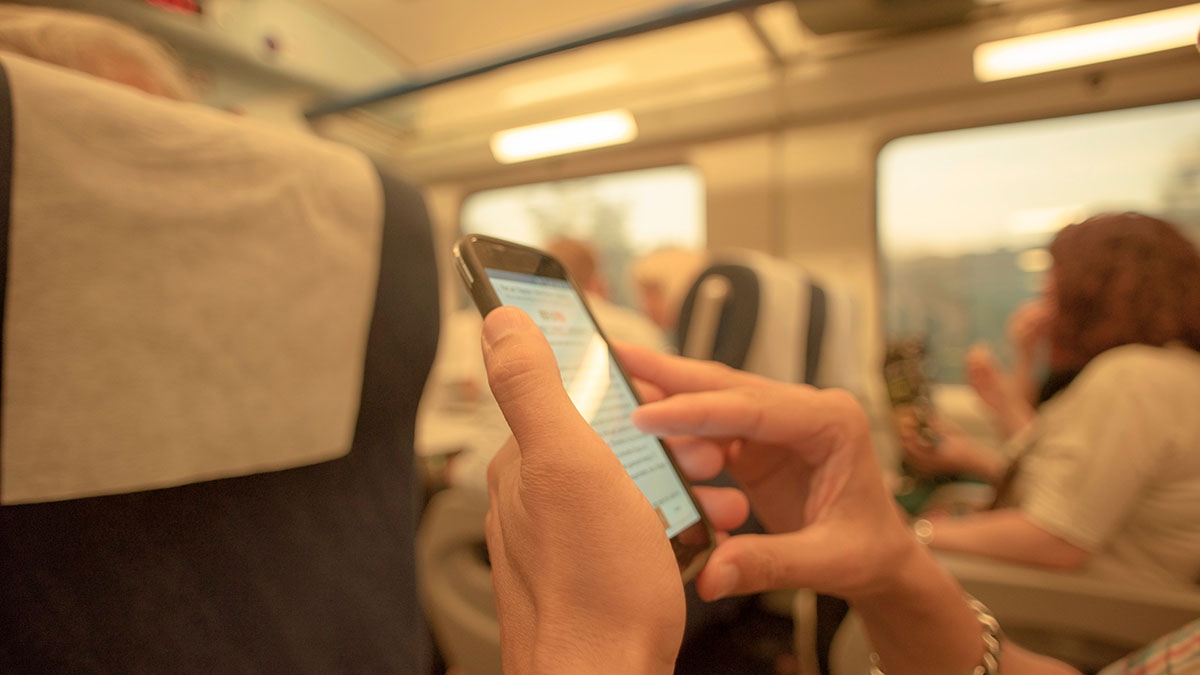 Eine Person im Zug hält ein Smartphone in der Hand Eine Person im Zug hält ein Smartphone in der Hand