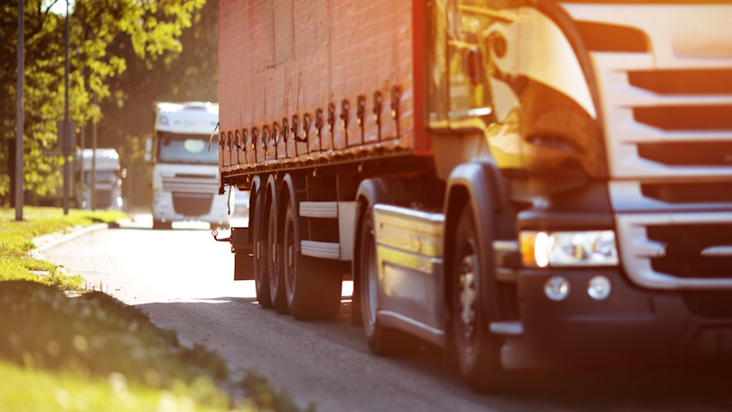 Lkw fahren an einem sonnigen Tag auf einer asphaltierten Straße Lkw fahren an einem sonnigen Tag auf einer asphaltierten Straße
