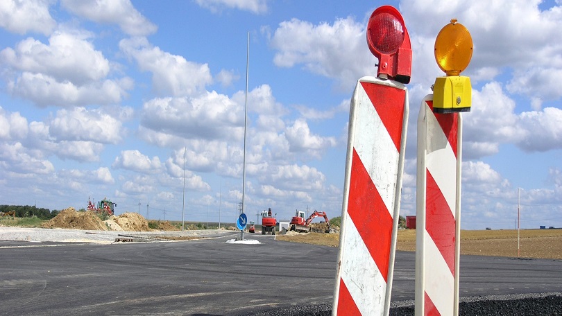 Straßenbaustelle mit Baggern im Hintergrund Straßenbaustelle mit Baggern im Hintergrund