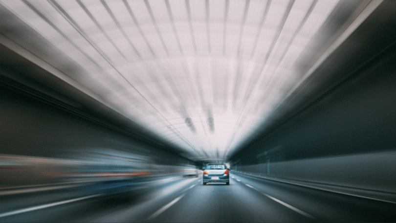 Aufnahme eines Pkw, der durch einen Tunnel fährt. Das Fahrzeug ist von hinten zu sehen. Die Umgebung ist unscharf dargestellt und deutet Bewegung und eine höhere Geschwindigkeit an. Aufnahme eines Pkw, der durch einen Tunnel fährt. Das Fahrzeug ist von hinten zu sehen. Die Umgebung ist unscharf dargestellt und deutet Bewegung und eine höhere Geschwindigkeit an.
