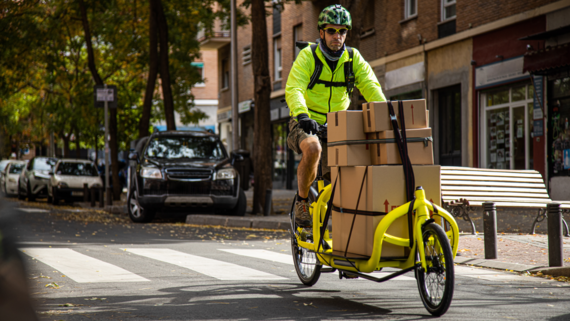 Eine Person transportiert mehrere Kartons auf einem Lastenrad Eine Person transportiert mehrere Kartons auf einem Lastenrad