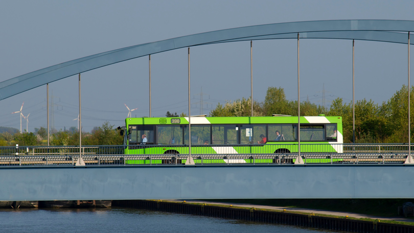 Grüner Bus auf Brücke über einem Fluss Grüner Bus auf Brücke über einem Fluss